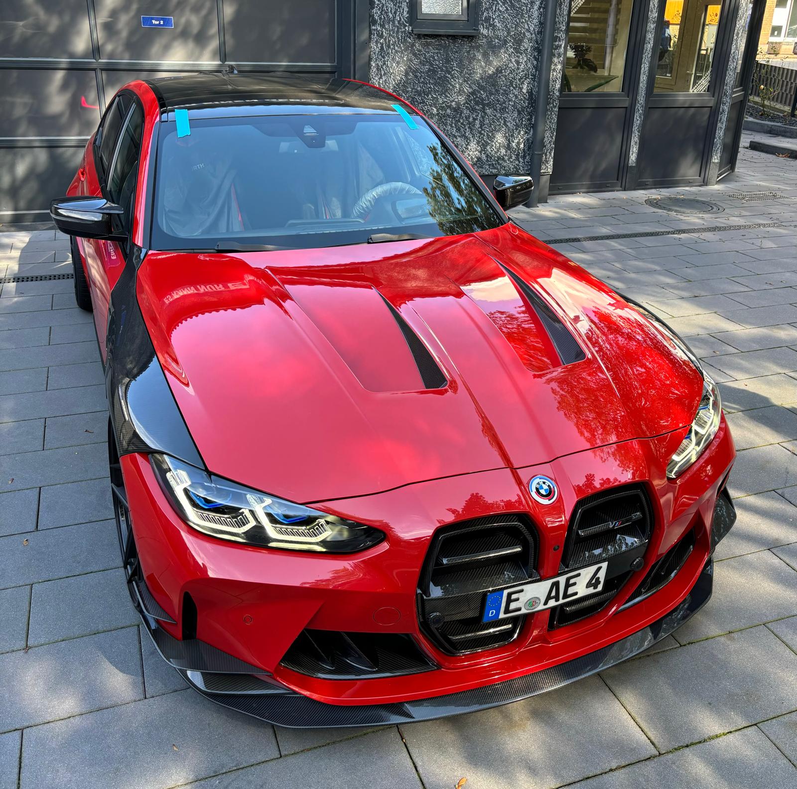 Ein roter BMW mit markanten schwarzen Akzenten und sportlichem Design, geparkt auf der Straße.