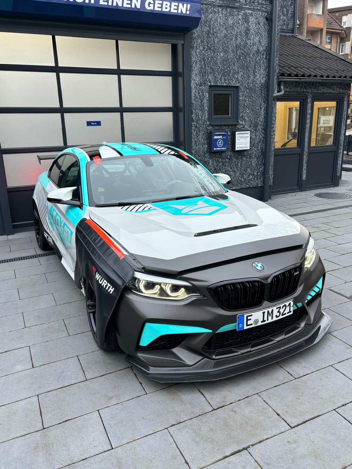 Ein modifiziertes weiß-türkises Auto mit sportlichem Design und markanten Lufteinlässen.